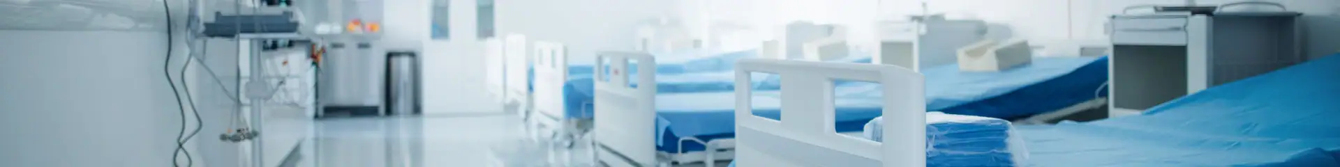 A row of hospital beds in a clean, well-lit medical facility with blue bedding, essential medical equipment, and a sterile environment for patient care and recovery.