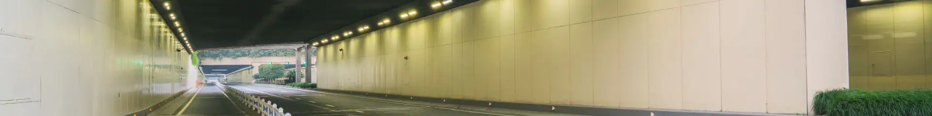 A modern, well-lit tunnel under an overpass with smooth road markings and a clean environment, ideal for safe vehicle passage. The setting emphasizes urban infrastructure and transportation efficiency.