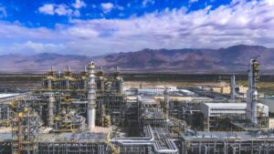 Large industrial ethylene production facility in Xinjiang Dushanzi, featuring complex piping, distillation columns, and processing units set against mountainous terrain.