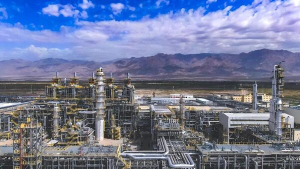 Large industrial ethylene production facility in Xinjiang Dushanzi, featuring complex piping, distillation columns, and processing units set against mountainous terrain.