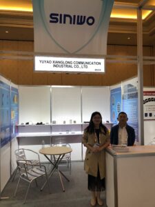 YUYAO XIANGLONG COMMUNICATION INDUSTRIAL CO., LTD. booth at trade show, showcasing communication technology products with two representatives standing in front of display panels.