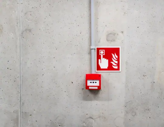 Fire alarm and emergency alert button mounted on a plain concrete wall, used for safety notifications and emergency response in commercial or industrial settings.