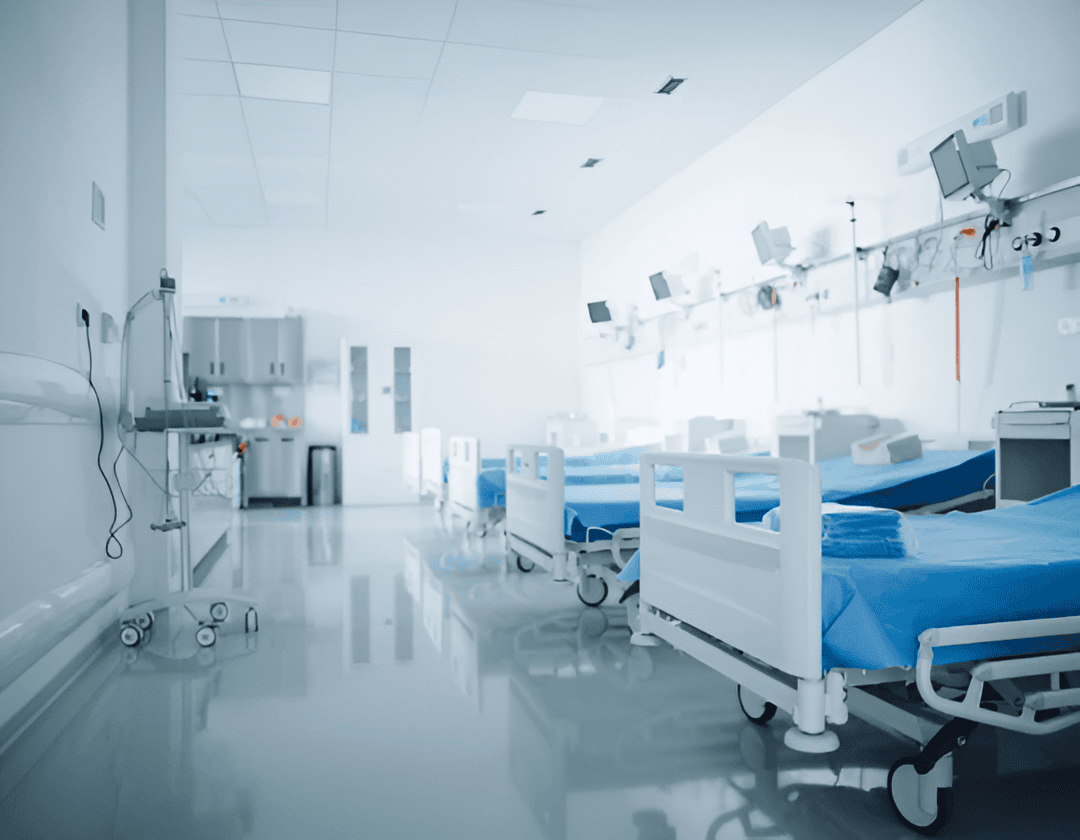 Modern hospital patient room with empty beds, medical monitors, and equipment in a clean, well-lit healthcare facility.