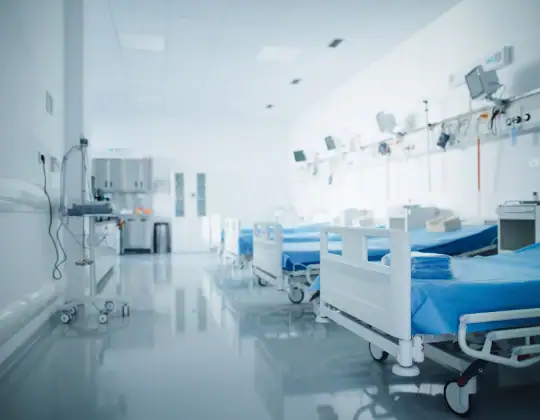 Hospital patient room with empty beds, medical monitors, and equipment in a clean, well-lit healthcare facility. Suitable for healthcare, hospital, and medical app themes.