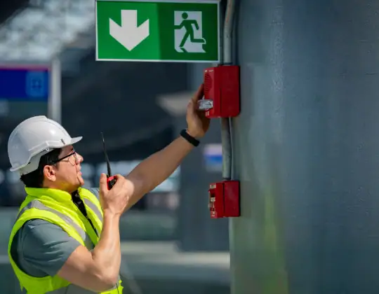 Emergency exit sign with green background and white symbols indicating the direction to safety.