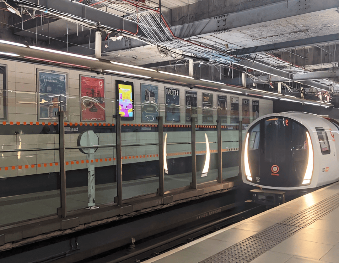 Autonomous metro train arriving at underground station with digital advertising screens and modern infrastructure.