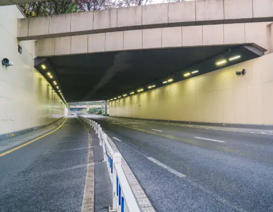 Underpass tunnel for vehicles with road markings and lighting, designed for smooth traffic flow.