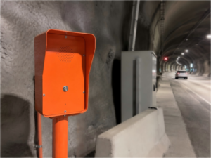 Orange emergency telephone station installed inside a road tunnel for safety communication in Norway.