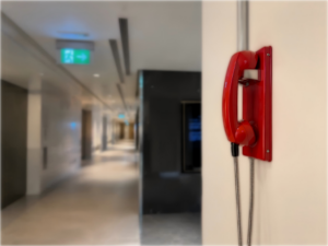Red fire emergency telephone mounted on a wall in a modern commercial building corridor in the UAE.