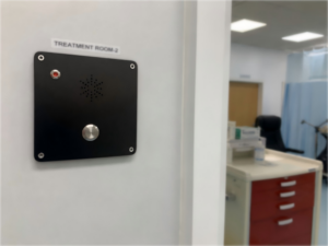 Hands-free telephone device installed in a healthcare facility treatment room for communication and safety.