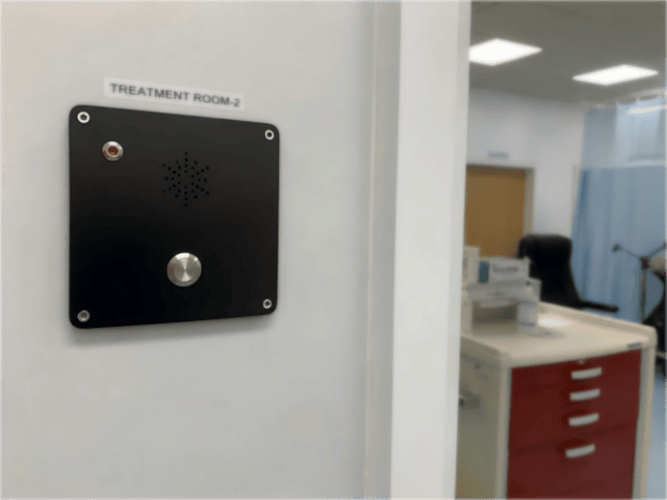 Hands-free telephone device installed in a healthcare facility treatment room for communication and safety.
